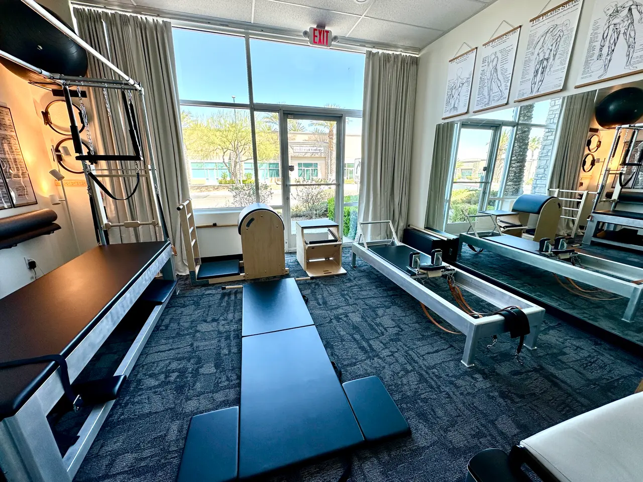 Classical Pilates studio in Southwest Las Vegas with traditional Reformers, a Ladder Barrel, and a mat area beneath anatomy charts
