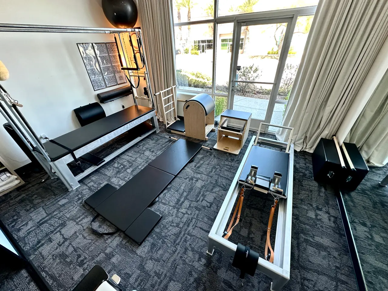 Fully equipped classical Pilates studio featuring a Reformer, Cadillac trapeze table, Wunda Chair, and spine corrector