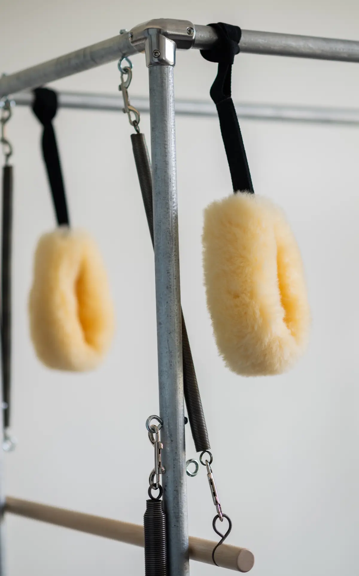 Close-up of sheepskin-lined straps and springs hanging from the Cadillac trapeze table frame