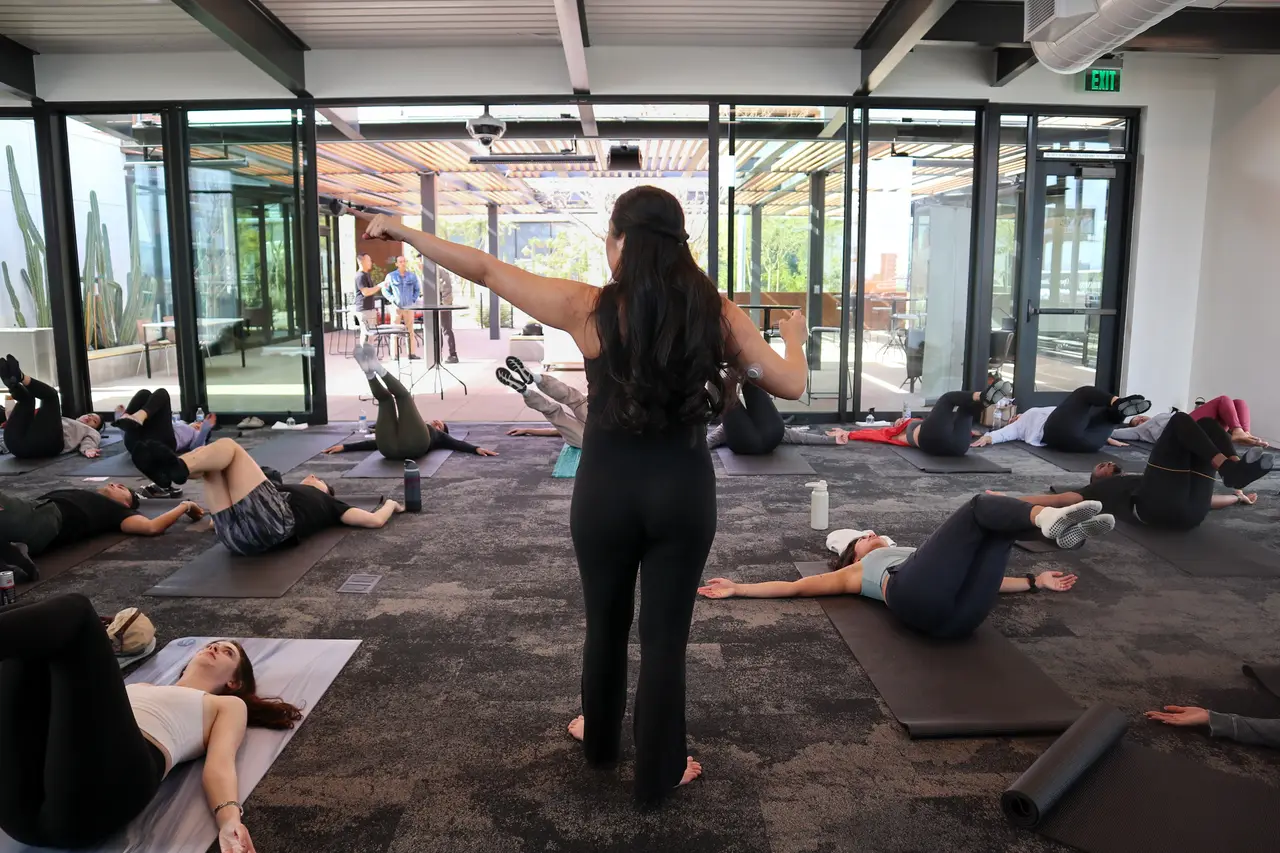 Group of people doing pilates on mats at an outdoor community event